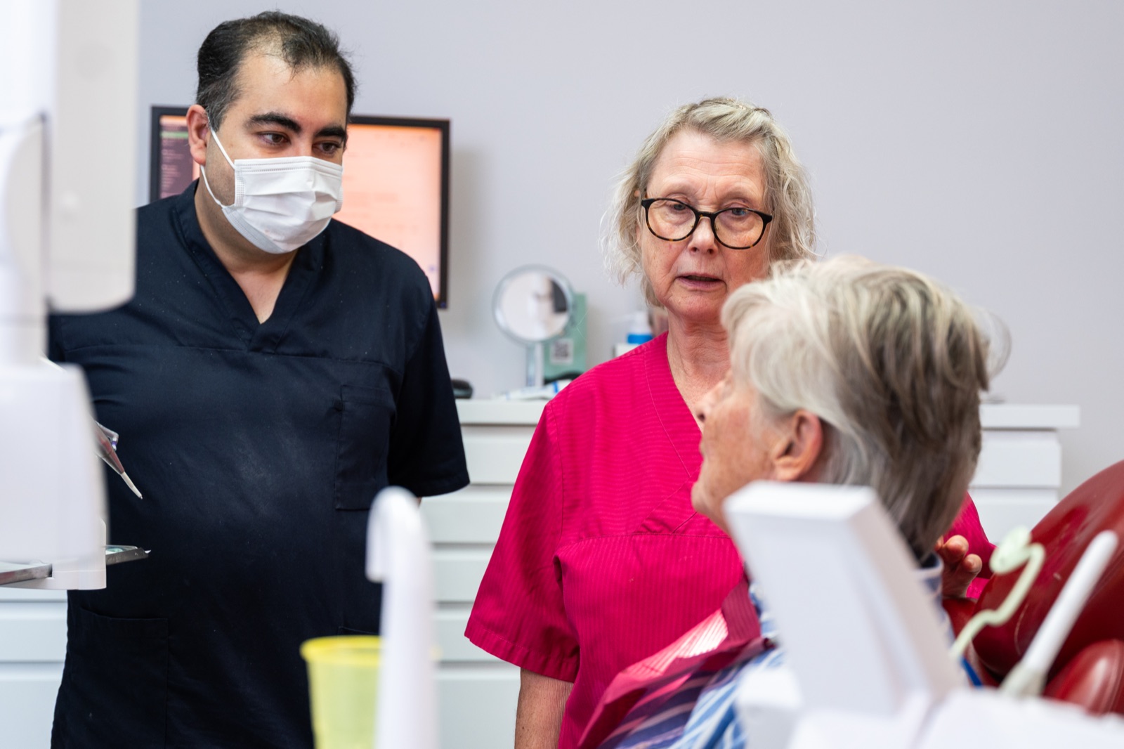 Tandläkaren Saeid och tandsköterskan Marie samtalar med en äldre patient i behandlingsstolen