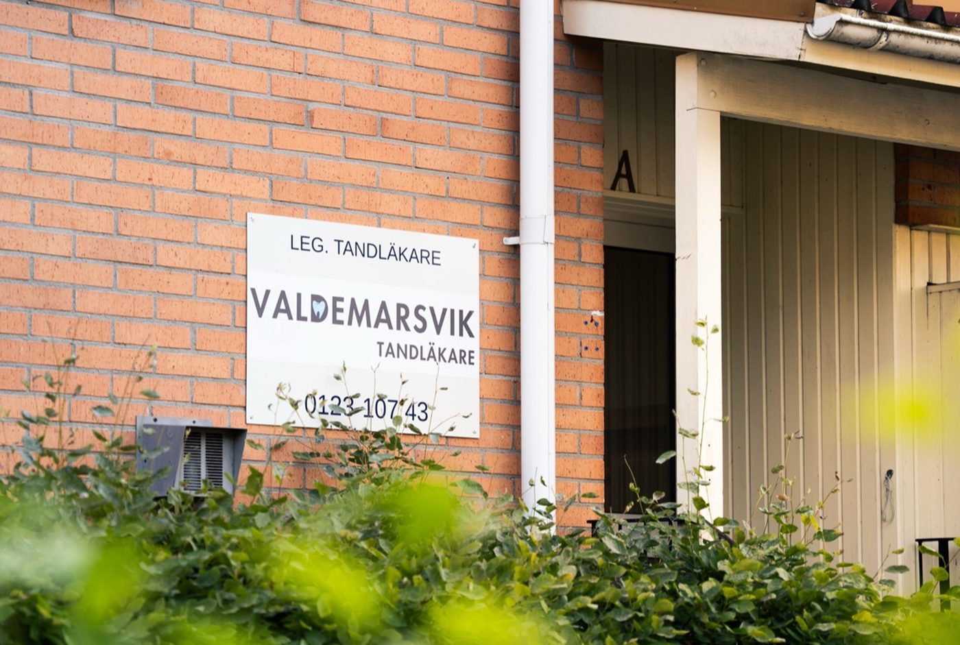 Skylten vid entrén: Leg. tandläkare, Valdemarsvik Tandläkare, 0123-107 43